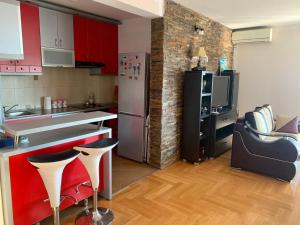 cocina con armarios rojos y nevera de acero inoxidable en Blue Sky Apartment, en Petrovac na Moru 15 fotos más