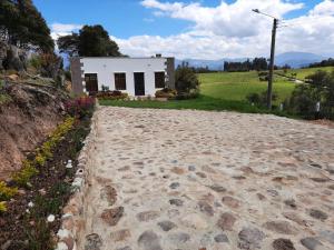 una carretera de piedra que conduce a una pequeña casa blanca en Cabaña Campestre Katie, en Paipa