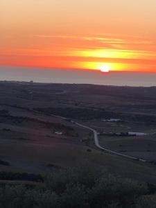 una puesta de sol sobre un campo con una carretera en Casas El Molino, en Vejer de la Frontera