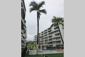 a hotel with a palm tree and a swimming pool at HERMOSO APARTA ESTUDIO en Melgar in Melgar +3 photos