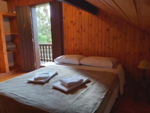 a bedroom with a bed with towels and a window at Chalé Andorinhas in Monte Verde