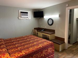 a bedroom with a bed and a desk and a television at Budget inn in Kingsville