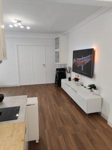 salon z białymi szafkami i telewizorem na ścianie w obiekcie APARTAMENTO LEVIES w Sewilli