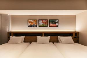 two beds in a bedroom with three pictures on the wall at Hotel Forza Osaka Namba in Osaka +37 photos