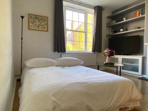 a bedroom with a white bed and a television at London Waterloo Apartment in London
