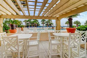 une terrasse avec des tables et des chaises blanches et une piscine dans l'établissement Villamare, à Île de Hilton-Head