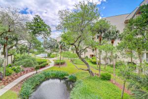 un jardin avec un étang en face d'un bâtiment dans l'établissement Villamare, à Île de Hilton-Head