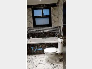 a bathroom with a toilet and a tub and a window at Private property in Cairo