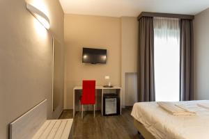 Hotel Terme di Frasassi في جينجا: غرفة في الفندق بها كرسي احمر ومكتب