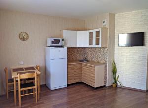 a small kitchen with a white refrigerator and a table at Studio on Molodogvardeytsev 76, Academ Riverside in Chelyabinsk
