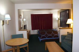 ShawanoにあるAmeriVu Inn and Suites Shawano WIのベッドとテーブルが備わるホテルルームです。