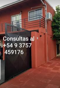 una casa roja con una puerta con un cartel. en Alojamiento El Jilguero en Puerto Iguazú