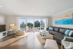 a living room with a black leather couch and a tv at Casa Sorella - beachfront family home with pool in North Haven