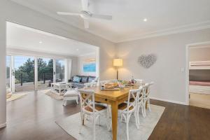 a dining room and living room with a table and chairs at Casa Sorella - beachfront family home with pool in North Haven