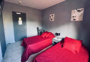 two beds in a room with red comforter at L organdi in Cornebarrieu