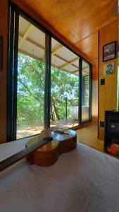 una guitarra sentada en una cama en una habitación con ventana en Casa da Árvore espaço Vila da Serra en Nova Lima