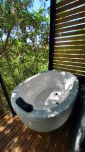 a bath tub sitting on a deck next to a window at Casa da Árvore espaço Vila da Serra in Nova Lima