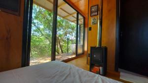 a bedroom with a bed and a large glass window at Casa da Árvore espaço Vila da Serra in Nova Lima