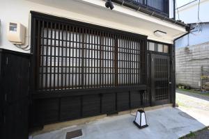 a black gate on the side of a house at Manabi-stay Matsue 駅近伊勢宮町どこに行くにも最高に便利な古民家一棟貸切ホテル in Matsue