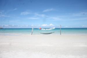 a boat sitting on a beach next to the ocean at Tommy Resort in Haad Rin