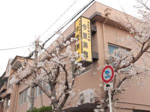a building with a sign in front of a tree at Imazato Ryokan in Osaka