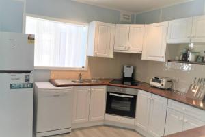 a kitchen with white cabinets and a sink at So close to Birubi Beach in Anna Bay