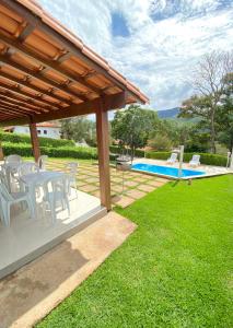 een patio met een tafel en stoelen en een zwembad bij Temporada Escarpas in Capitólio