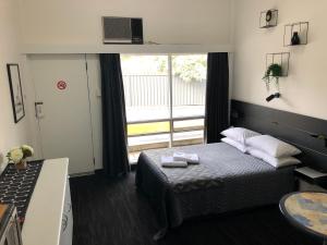 a small bedroom with a bed and a window at Blue Gums Hotel Motel in Teatree Gully