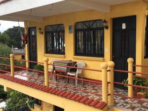 a yellow house with a table and chairs on a balcony at Hotel Villa del Lago in San Pedro La Laguna