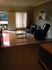 a living room with two chairs and a coffee table at Francis Phillip Motor Inn and The Lodge in Singleton