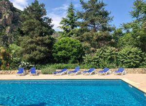 a swimming pool with blue chairs and a swimming pool at A l'ombre du Fort in Fuilla