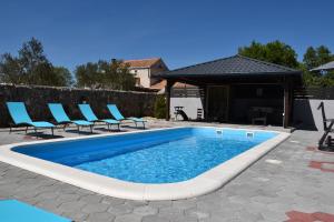 a swimming pool with blue chairs and a table at Villa Luna in Biograd na Moru