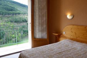 ein Schlafzimmer mit einem Bett und einem großen Fenster in der Unterkunft Hôtel Des Rochers in Marvejols