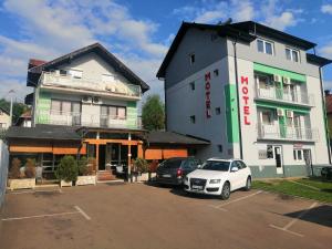 a white car parked in a parking lot in front of a building at Motel Aura in Višegrad