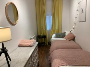 two beds in a room with a mirror and a table at SG Apartamentos LA CASA DE LA CATEDRAL VUT47-240 in Valladolid