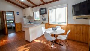 cocina con mesa blanca, sillas y fregadero en Bellarine Bayside Portarlington en Portarlington