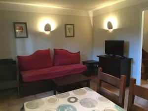 Una sala de estar con un sofá rojo y un televisor. en Jolie petite maison à Vieux Boucau avec piscine chauffée - Domaine du Golf de Pinsolle, en Soustons