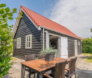 a table with chairs and a small house at 't Schouws Uusje in Burgh Haamstede