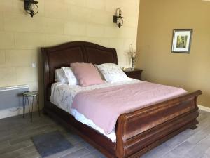 a bed with a wooden frame in a bedroom at Chateau Couchebout in Pugnac