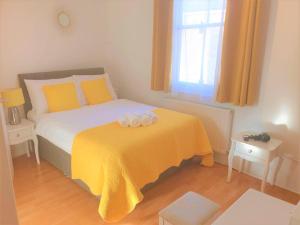 a bedroom with a bed with a yellow blanket at Julian apartment center of London in London +3 photos