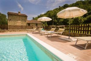 einen Pool mit Stühlen und Sonnenschirmen neben einem Haus in der Unterkunft Il Mulino - beautiful, family-friendly Tuscan villa with fenced pool in Monterchi