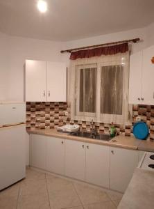 a kitchen with white cabinets and a sink and a window at ziogas apartments in Plataria