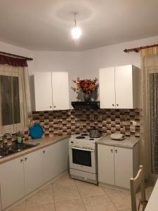uma cozinha com armários brancos e um forno com placa de fogão em ziogas apartments em Plataria