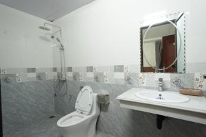 La salle de bains est pourvue de toilettes, d'un lavabo et d'un miroir. dans l'établissement HOẰNG MINH HOTEL, à Sầm Sơn