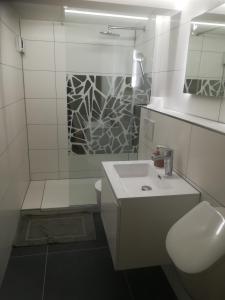 ein weißes Bad mit einem Waschbecken und einer Dusche in der Unterkunft Ferienwohnung im Hain in Bamberg