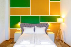 1 dormitorio con 1 cama con una pared colorida en H11 Downtown Apartments, en Târgu Mureș