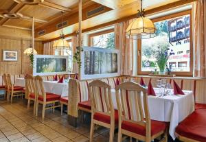 un restaurante con mesas y sillas blancas y ventanas en Gasthof Hotel Schermer en Bad Häring