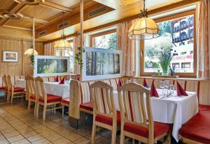 um restaurante com mesas e cadeiras brancas e janelas em Gasthof Hotel Schermer em Bad Häring