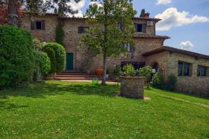 an old stone house with a green yard at PODERE Piazza di Sopra in Reggello