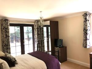 a bedroom with a bed and a tv and windows at Little Hermitage in Detling